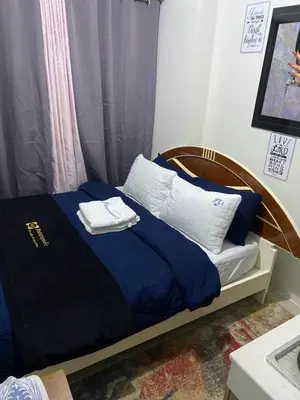 a small bed with blue sheets and white pillows at Collins Condotel in Manila