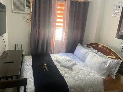 a small bedroom with a bed with a window at Collins Condotel in Manila