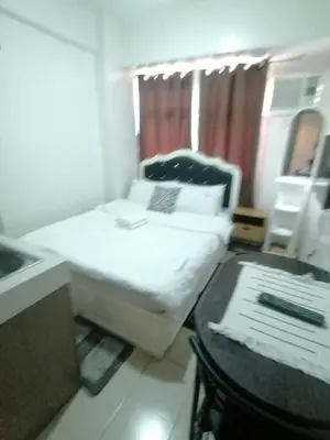 a small room with a bed with a laptop on it at Collins Condotel in Manila
