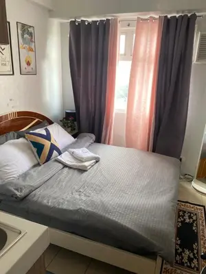 a small bedroom with a bed with a window at Collins Condotel in Manila