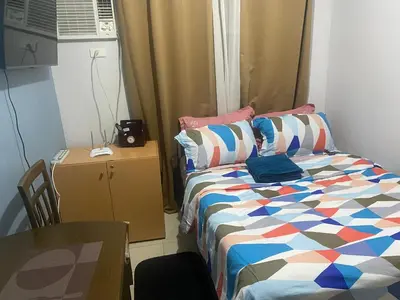 a small bedroom with a bed and a table at Collins Condotel in Manila