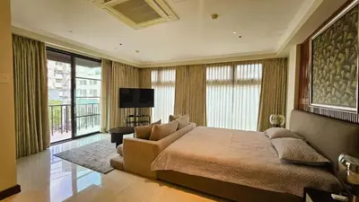 a bedroom with a large bed with a couch and a television at Poblacion Studio Apartment with Balcony in Manila