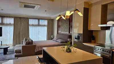 a kitchen and living room with a bed and a couch at Poblacion Studio Apartment with Balcony in Manila