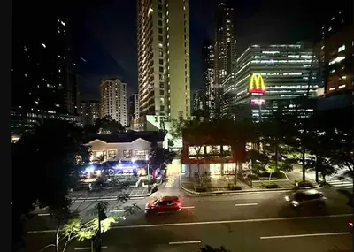 a city street at night with cars on the road at 2BR in Central BGC in Manila