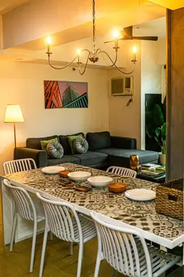 a living room with a table with chairs and a couch at 2BR in Central BGC in Manila