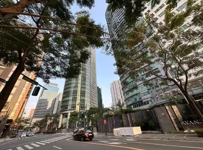 a car driving down a city street with tall buildings at 2BR in Central BGC in Manila