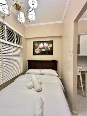 a large white bed in a bedroom with a chandelier at Studio Two Condominium, Alabang AMBER -Fiber WI-FI Netflix ready in Manila