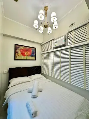 a bedroom with a large white bed with a chandelier at Studio Two Condominium, Alabang Northgate Cyberzone, DOVE-Fiber Wi-Fi Netflix ready in Manila
