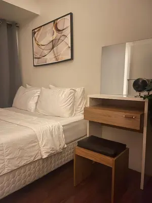 a bedroom with a bed and a table with a mirror at Destina, 100Mbps at Air Residences, Makati, MetroManila, Netflix in Manila