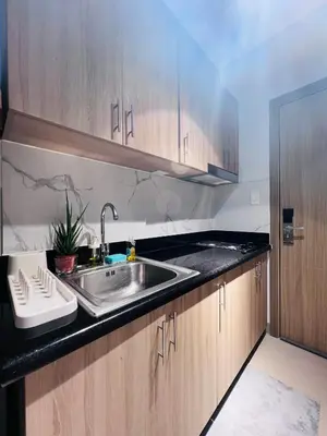 a kitchen with a stainless steel sink and wooden cabinets at Cozy Suite Pool View in Shore 2 Residences near SM MOA in Manila