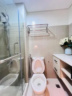 a bathroom with a toilet and a shower at Cozy Suite Pool View in Shore 2 Residences near SM MOA in Manila
