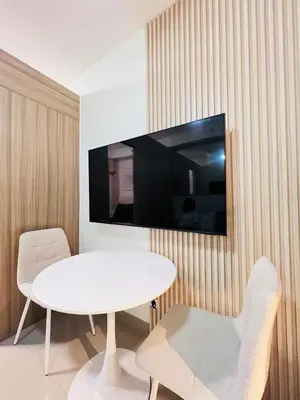 a room with a white table and a tv on a wall at Cozy Suite Pool View in Shore 2 Residences near SM MOA in Manila