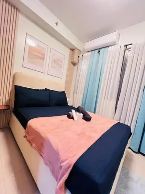a bed with a pair of shoes sitting on it at Cozy Suite Pool View in Shore 2 Residences near SM MOA in Manila