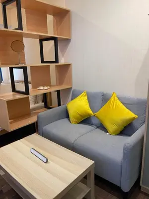 a living room with a blue couch with two yellow pillows at Destina, 100Mbps at Air Residences, Makati, MetroManila, Netflix in Manila