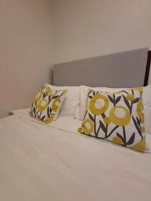 a bed with yellow and white pillows on it at Stylish and Comfy Condominium in Manila