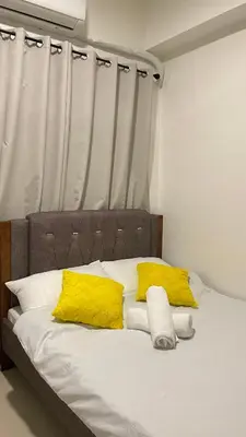 a bed with two yellow pillows at Staycation Bliss at Fame in Manila