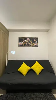 a bedroom with a bed with two yellow pillows at Staycation Bliss at Fame in Manila
