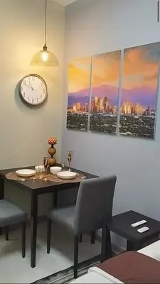 a dining room with a table and a clock on the wall at Premium Studio in Pioneer Mandaluyong in Manila
