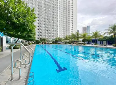 a large swimming pool in front of a tall building at Charming 2 Bedroom Makati Condo in Manila