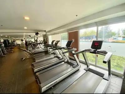 a row of treadmills in a gym with a large window at Charming 2 Bedroom Makati Condo in Manila