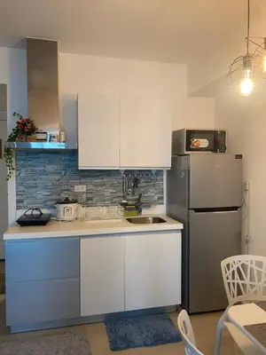 a kitchen with white cabinets and a refrigerator at Condotel Azure Beachview in Manila