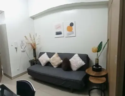 a living room with a blue couch with pillows at Shore 2 Staycation nice Homes in Manila