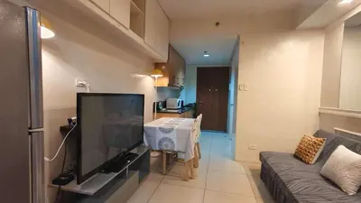 a living room with a flat screen tv and a couch at Family room big balcony pool view 2F in Manila