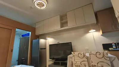 a living room with a tv and a couch at Family room big balcony pool view 2F in Manila
