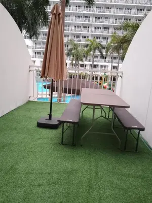a patio with a table and an umbrella and grass at Family room big balcony pool view 2F in Manila