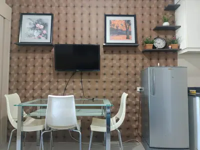 a dining room with a table and a television on a wall at Theresa Sea Residence Tower EF in Manila