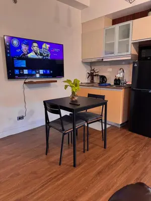 a kitchen with a table and a tv on a wall at Condo in Mckinley Hill Taguig in Manila
