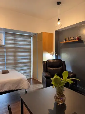 a bedroom with a bed and a chair and a table at Condo in Mckinley Hill Taguig in Manila