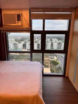 a bedroom with a view of a city from a window at Condo in Mckinley Hill Taguig in Manila