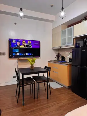 a kitchen with a table and a tv on the wall at Condo in Mckinley Hill Taguig in Manila
