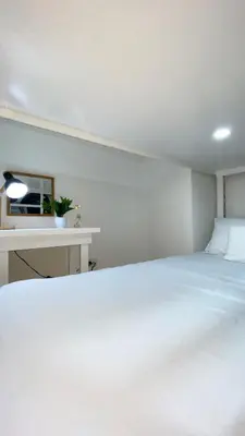a bedroom with a large white bed and a desk at Cozy SpaciousLoft near MRT BONI in Manila
