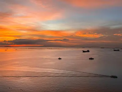a sunset on a beach with boats in the water at 175 Sqm Luxurious Modern 3 Bedrooms Facing Manila Bay Sunset, Airports, Okada, Solaire, MOA in Manila