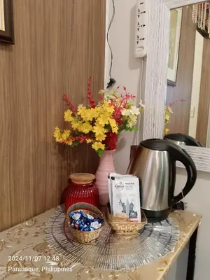 a table with a vase with flowers and a tea kettle at Benjamin's crib staycation in Manila