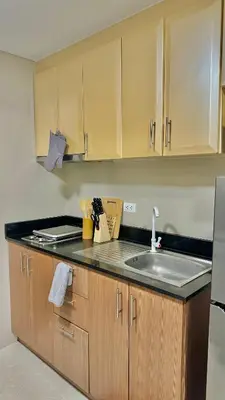 a kitchen with a sink and wooden cabinets at Newport City across NAIA Terminal 3 by II JDs Aparthotel in Manila