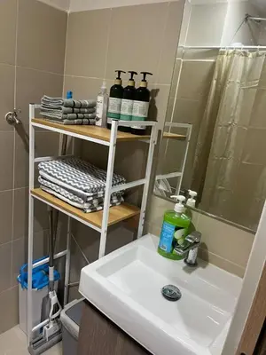 a bathroom with a white sink and a shower at Cozy Urban Nest in Manila