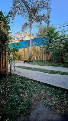 a fence with a palm tree next to a sidewalk at Natural Haven with Netflix Kubo Videoke & Alfresco Dining in Dasmariñas
