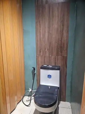 a bathroom with a toilet with a wooden wall at Natural Haven with Netflix Kubo Videoke & Alfresco Dining in Dasmariñas