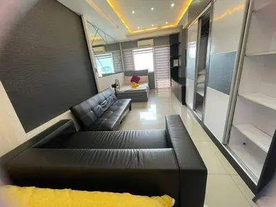 a living room with a black leather couch in a room at 1553 Moa view bigcut in Manila