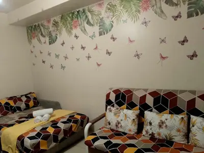 a bedroom with a bed and a couch with butterflies on the wall at 1103- 1bedroom 1 sofa bed 1 folding bed in Manila