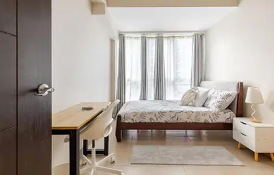 a bedroom with a desk and a bed and a desk and a window at BGC Taguig Uptown 3BR corner unit with pool view, bath tub, wifi, parking, beside Landers BGC in Manila