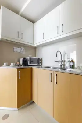 a kitchen with white cabinets and a sink at BGC Taguig Uptown 3BR corner unit with pool view, bath tub, wifi, parking, beside Landers BGC in Manila