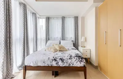 a bedroom with a bed with curtains and a window at BGC Taguig Uptown 3BR corner unit with pool view, bath tub, wifi, parking, beside Landers BGC in Manila