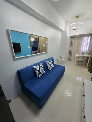 a blue couch in a living room with a tv at 1BR Solana Suite 5 at Coast Residences in Manila