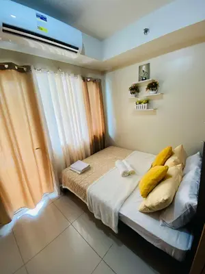 a bedroom with a bed with yellow pillows on it at 333D- 1br 1folding bed pool view in Manila