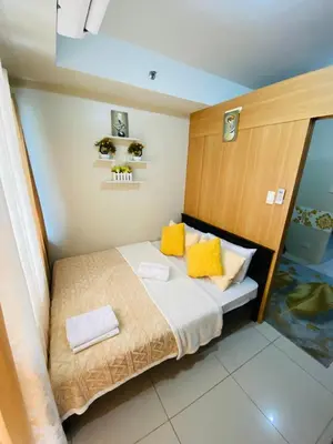 a small bedroom with a bed with yellow pillows at triple-D in Manila