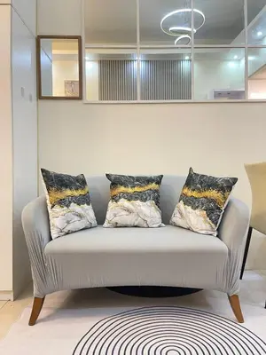 a couch with pillows on it in a living room at Orchids Shore Residences Direct Pool Access in Manila